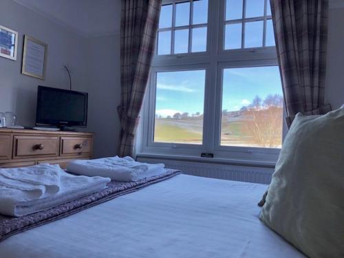 a bedroom with a bed with a television and a window at Meadowcroft Guest House in Windermere