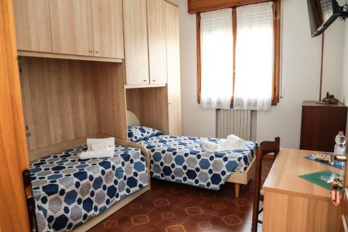 にあるGuest House Via Emiliaのベッド2台とテーブルが備わる小さな客室です。
