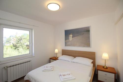 a bedroom with two beds and a window at Apartman Milena in Punat