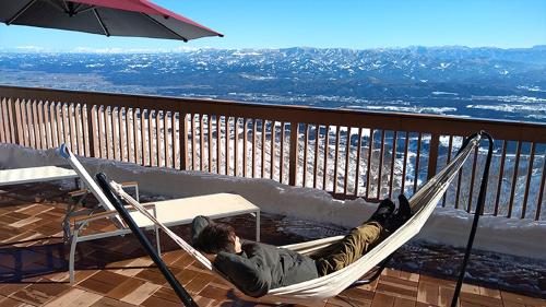 a man laying in a hammock on a balcony at Lotte Arai Resort in Myoko