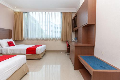 um quarto de hotel com duas camas e uma janela em RedDoorz Premium at Hotel Ratu Residence em Palmerah