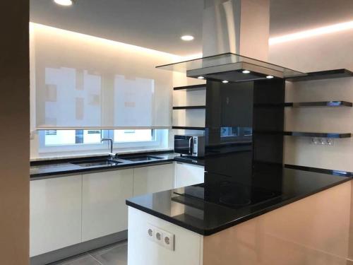 une cuisine avec un comptoir noir et des armoires blanches dans l'établissement Casa do Sul Guest House, à Lagos