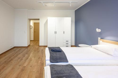 a white bedroom with two beds and a closet at Kastani Factory Apartments in Tartu
