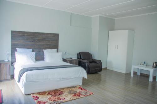 a bedroom with a large white bed and a chair at Neat one bedroom in Morningside guesthouse - 2089 in Bulawayo