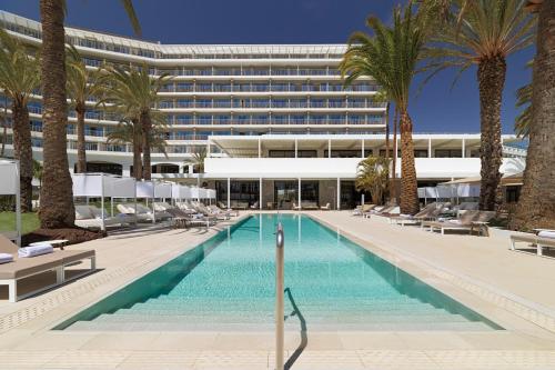 a swimming pool with palm trees and a building at Paradisus Gran Canaria in San Agustin