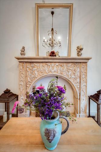 a vase with purple flowers on a table in front of a fireplace at Purple Dog Suites in León