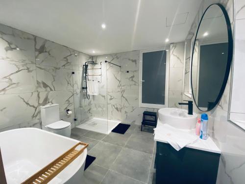 a white bathroom with a sink and a mirror at Spacious Deluxe Seaside Escape in St Paul's Bay