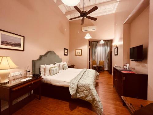 a bedroom with a bed and a desk and a ceiling fan at The Elgin Fairlawn, Kolkata in Kolkata