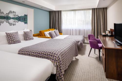 a hotel room with two beds and a desk at Mercure Swansea Hotel in Swansea