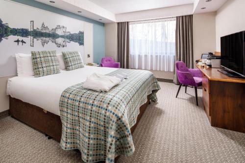 a hotel room with a bed and a desk and a television at Mercure Swansea Hotel in Swansea