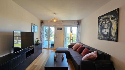 a living room with a couch and a television at Arbre Blanc, une folie montpelliéraine in Montpellier