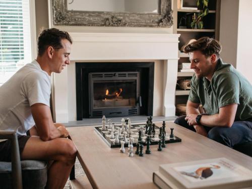 two men playing a game of chess in a living room at Woodlands Villa in George