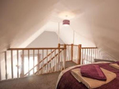a attic room with a bed and a staircase at Little Rigg Cottage in Pickering