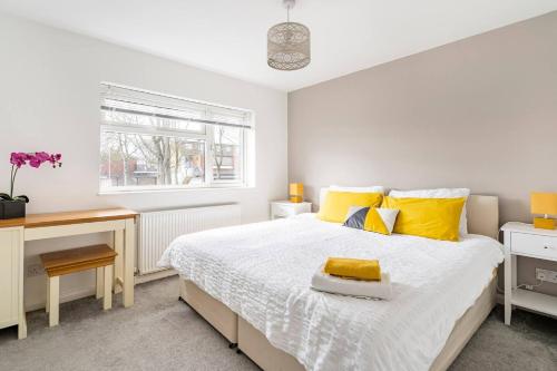 um quarto com uma cama com almofadas amarelas e uma secretária em Stevenage Contractors x8 New 3 bedroom House Free Wifi, Parking, Towels all inclusive & Large Garden em Stevenage