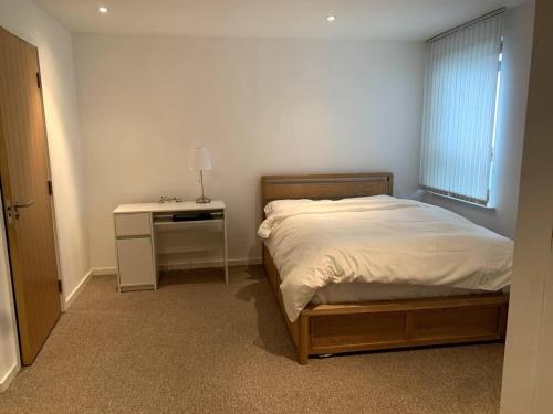a bedroom with a bed and a desk and a window at Large Private Flat in City Centre Leeds in Leeds