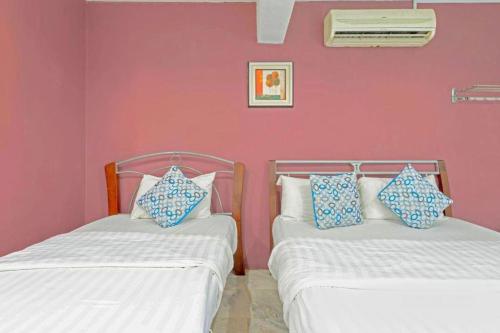 two beds in a room with a pink wall at GS Golden Star Hotel in Seri Kembangan