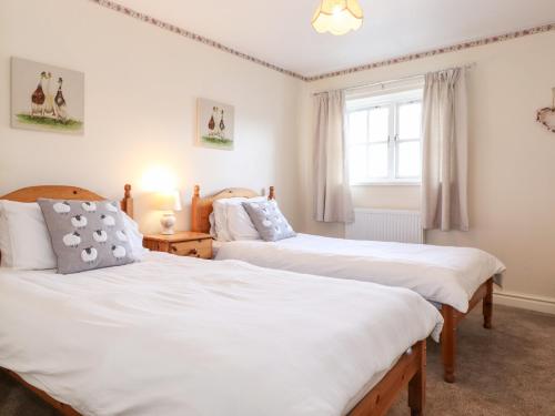 1 dormitorio con 2 camas y ventana en Swallows Nest Cottage, en Ambleside