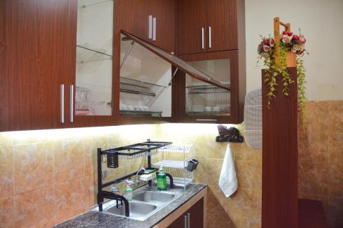 a kitchen with a sink and wooden cabinets at Roemah Canting Homestay in Yogyakarta