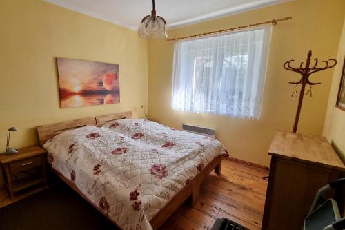 um quarto com uma cama com um edredão e uma janela em Ferienhaus "Ullersdorfer Teiche" em Ullersdorf