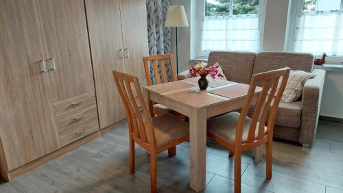 a dining room table with two chairs and a vase with flowers at Ferienwohnung "Jasmund" in Sagard auf Rügen in Sagard