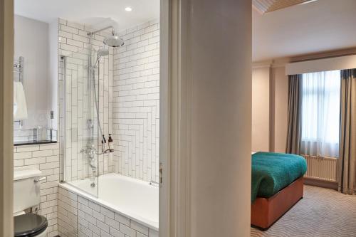 a bathroom with a tub and a toilet and a sink at Kimpton Clocktower by IHG in Manchester