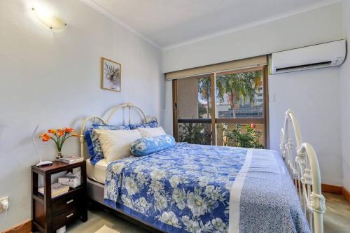 a bedroom with a bed with a blue comforter and a window at Joyful Esplanade City Stay in Darwin