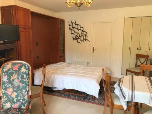 - une chambre avec un lit, une chaise et une télévision dans l'établissement Studio Calme à 5min de l'Océan - Parking et Balcon Aménagé - FR-1-4-521, à Saint-Jean-de-Luz