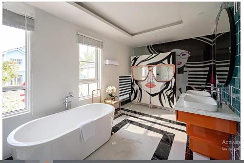 a bathroom with a tub and a painting of a woman at Novaworld Villas in Phan Thiet