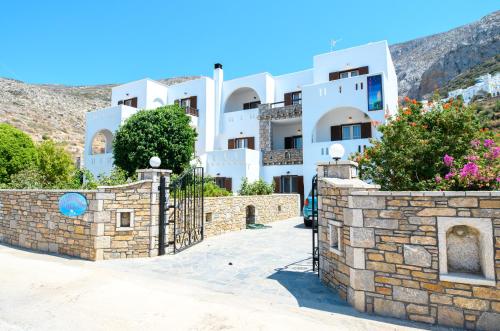 une villa avec une clôture en pierre en face d'un bâtiment dans l'établissement Villa Andromeda, à Amorgós