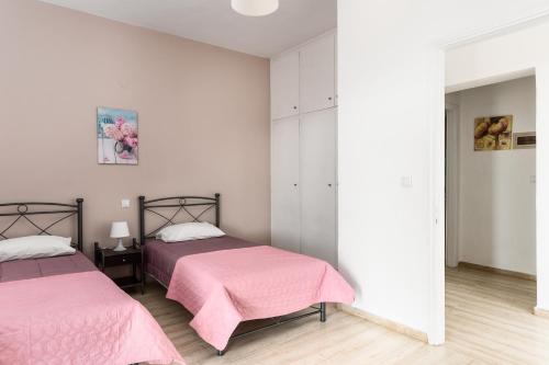 two beds in a white room with pink sheets at Katerina Horizon Apartments by Konnect - 1,8km from Ipsos beach in Ýpsos