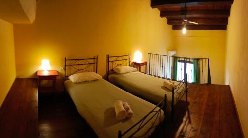 マツァーラ・デル・ヴァッロにあるMulino Bonacasaの黄色の壁とランプ2つが備わる客室のベッド2台
