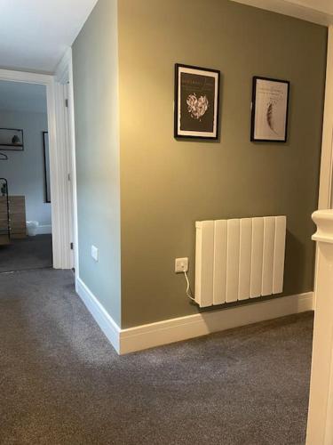 a hallway with a green wall with a radiator at Cedar House by ShortStays4U A modern 2 bedroom house with free parking in town centre! in King's Lynn