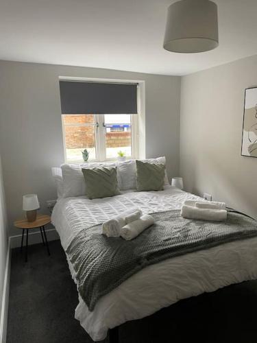 a bedroom with a bed with two towels on it at Cedar House by ShortStays4U A modern 2 bedroom house with free parking in town centre! in King's Lynn