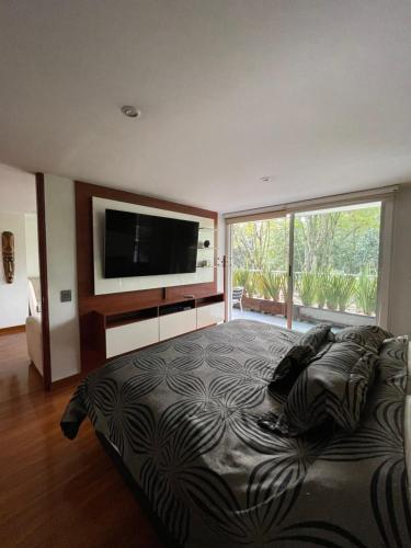 um quarto com uma cama grande e uma televisão de ecrã plano em Lujoso Apartamento parque el Virrey em Bogotá