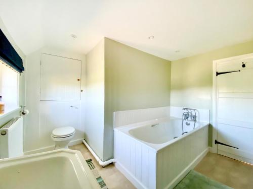 a white bathroom with a tub and a toilet at Keepers Cottage in Petersfield