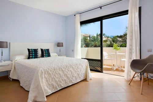 a white bedroom with a bed and a balcony at Villa Pueblo Don Thomas in San Sebastián de la Gomera