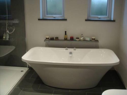 een badkamer met een wit bad en een raam bij Farriers Fold in Grange Over Sands