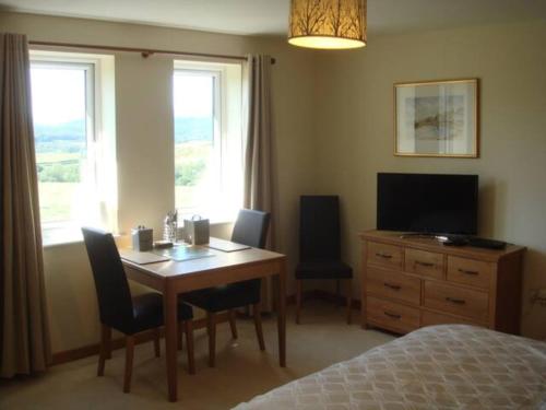 een slaapkamer met een tafel, een televisie en een bed bij Farriers Fold in Grange Over Sands