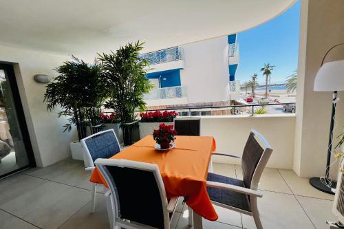 - une salle à manger avec une table et des chaises orange dans l'établissement Villa Marie 1 - Superbe appartement climatisé 2 chambres Vue Mer, au Grau-du-Roi