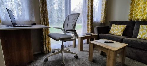 uma sala de estar com uma secretária, uma cadeira e um sofá em Billing Aquadrome, Kingfisher Meadows 12 em Great Billing