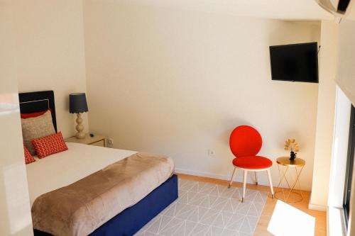 a bedroom with a bed and a red chair at Fish Village Terrace Luxo in Vila Nova de Gaia