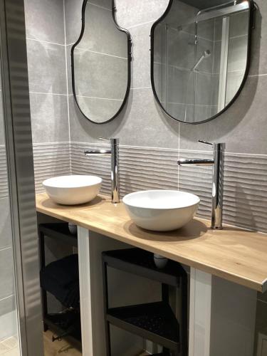 une salle de bains avec deux lavabos et deux miroirs sur un comptoir dans l'établissement L’INSOLITE, à Pierry