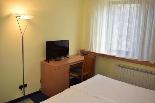 a hotel room with a desk with a television and a bed at Hotel Tomislavov Dom in Zagreb