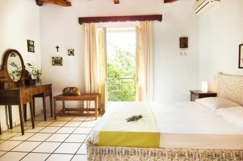 a bedroom with a bed and a desk and a window at Drakos Vacation Houses in Stoupa