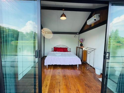 a bedroom with a bed and sliding glass doors at เรือนแพคุณมน-Khun Mon Raft in Kanchanaburi