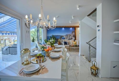 a dining room with a white table with a chandelier at Villa Santorini in Konarzyny