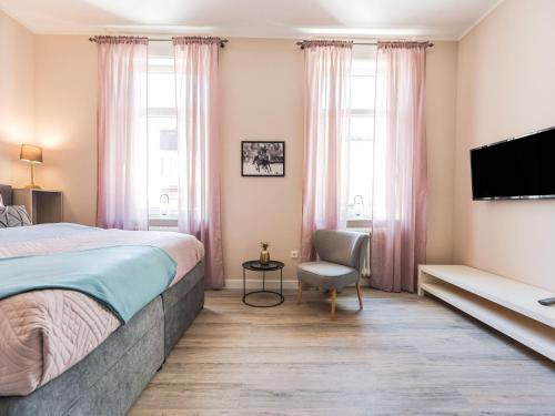 a bedroom with a bed and a tv and a chair at Charmante Suite für entspannte Tage in Bad Camberg