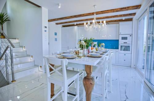 a white dining room with a white table and chairs at Villa Santorini in Konarzyny