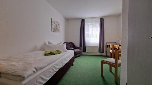 ein kleines Schlafzimmer mit einem Bett und einem Stuhl in der Unterkunft Hotel Asterra in Saalfeld