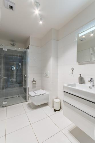 a white bathroom with a sink and a shower at Perfekt Apartments 5 Mórz Sianożęty in Sianozety